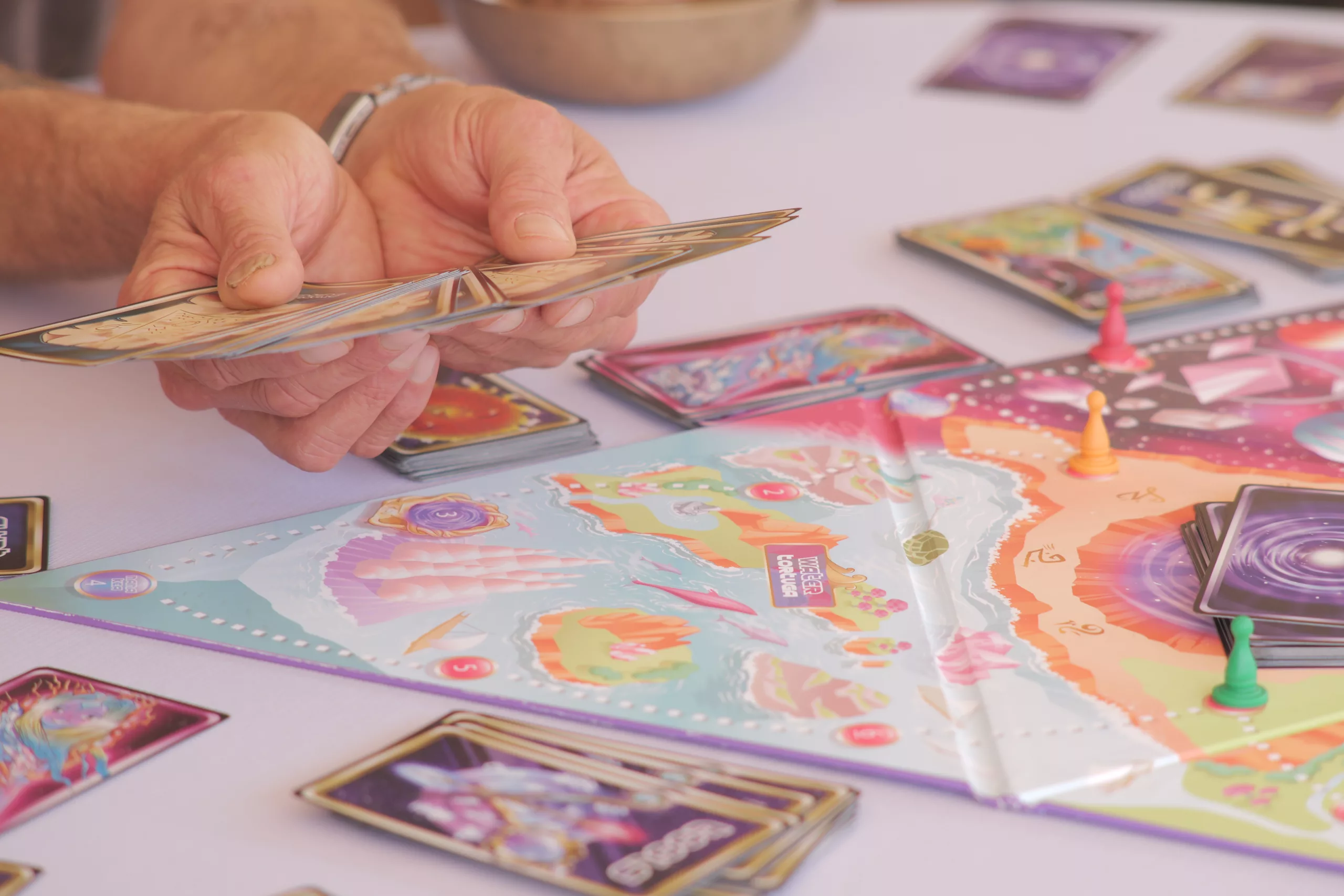 Hands holding Sacred Worlds cards during gameplay